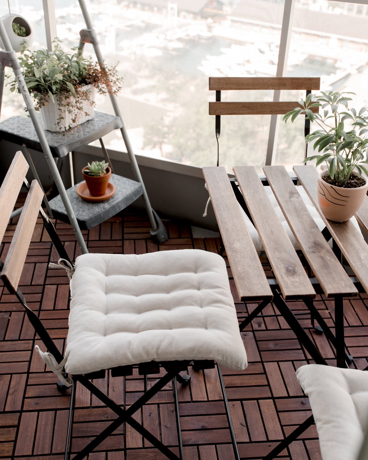 A clean balcony deck with a folding chair, white cushion and plants