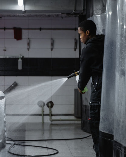 Rinsing a car with a pressure washer in a garage