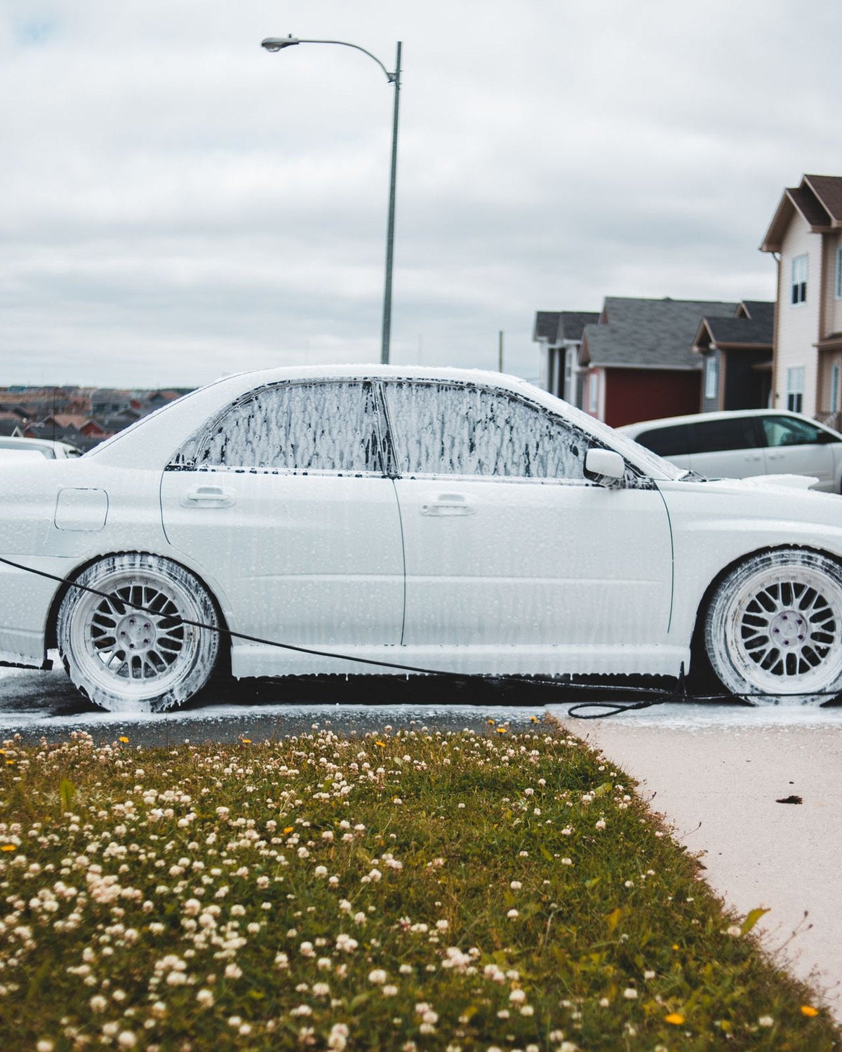 A foamed car being washed on a driveway